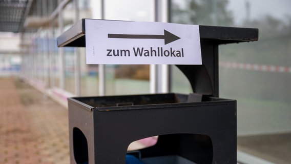 Auf einem öffentlichen Mülleimer ist ein Hinweisschild angebracht, dass die Richtung zu einem Wahllokal anzeigt. © picture alliance/dpa Foto: Christophe Gateau