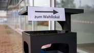 Auf einem öffentlichen Mülleimer ist ein Hinweisschild angebracht, dass die Richtung zu einem Wahllokal anzeigt. © picture alliance/dpa Foto: Christophe Gateau
