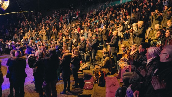 Das Publikum bei der Freilichtbühne Krusenkoppel ist auf den Füßen und singt und klatscht mit. © NDR Foto: Yosua Pandelaki