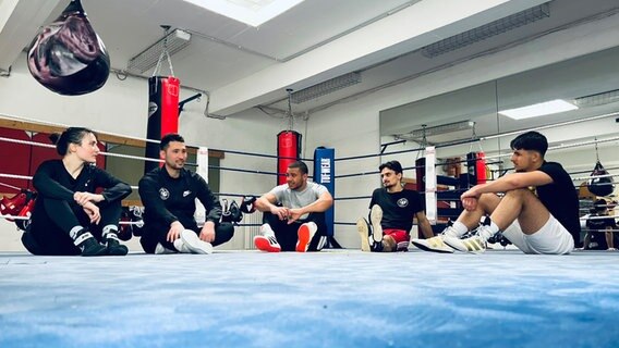 Boxer sitzen im Boxring und tauschen sich aus. © NDR Foto: Berit Ladewig