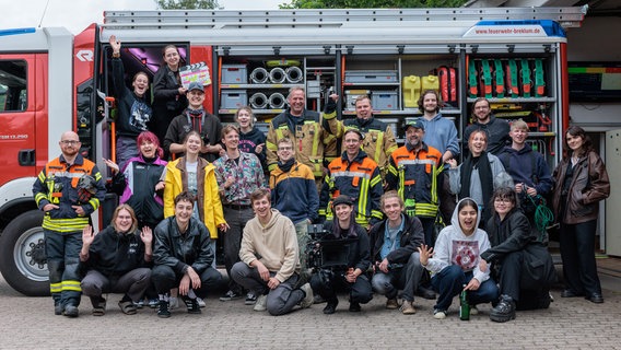 Vor einem Feuerwehrfahrzeug stehen viele junge Menschen, einige weitere davon in Feuerwehrkleidung. © Meike Clausen Foto: Henner Feddersen