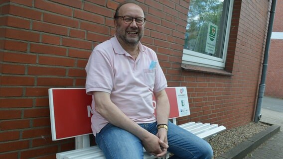 Peter Kroll, der Bürgermeister von Alveslohe, sitzt auf der Mitfahrerbank vor seinem Gemeindehaus. © NDR Foto: Anne Passow