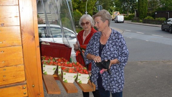 Marita Beine, die Kümmerin von Alveslohe und Annemarie Lepthin stehen am Erdbeerstand. © NDR Foto: Anne Passow