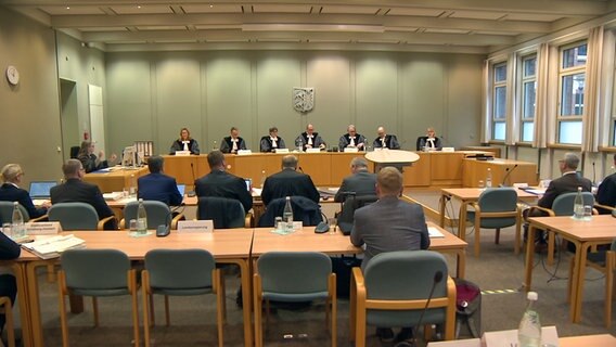 Menschen sitzen in einem Gerichtssaal des Landesverfassungsgerichts in Schleswig. © NDR 