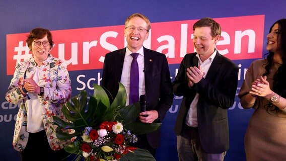 Daniel Günther (CDU/M), Ministerpräsident von Schleswig-Holstein und Spitzenkandidat seiner Partei, hält nach Bekanntgaben der ersten Prognosen zur Landtagswahl in Schleswig-Holstein bei der Wahlparty Blumen in die Höhe. © dpa-Bildfunk Foto: Christian Charisius/dpa