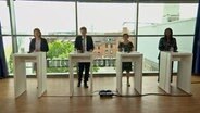 Karin Prien, Daniel Günther, Monika Heinold und Aminata Touret (v. l. nach r.) stehen in einem Raum in der Wunderinoarena in Kiel bei einer Pressekonferenz. © NDR 