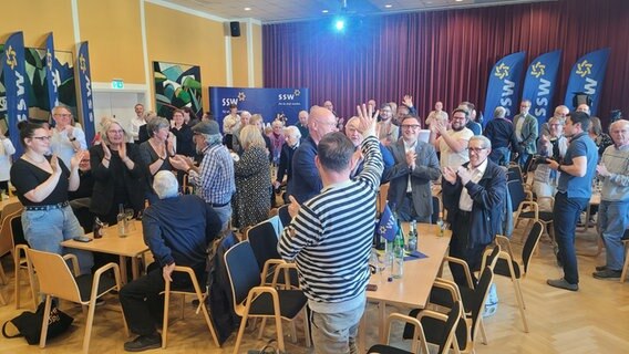 Mehrere Personen stehen auf einer Wahlparty der SSW. © Frank Goldenstein/NDR Foto: Frank Goldenstein