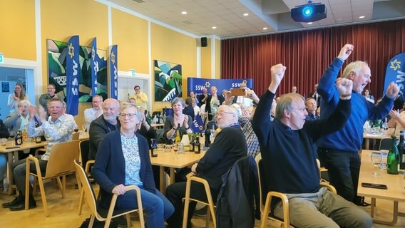 Mehrere Personen stehen auf einer Wahlparty der SSW. © Frank Goldenstein/NDR Foto: Frank Goldenstein