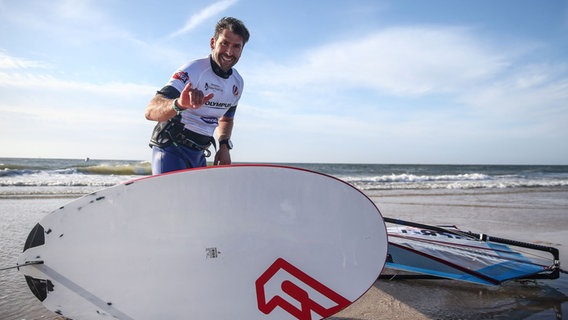Windsurfer Vincent Langer steht am Strand vor seinem Surfbrett. © picture alliance / HOCH ZWEI /Joern Pollex Foto: Joern Pollex
