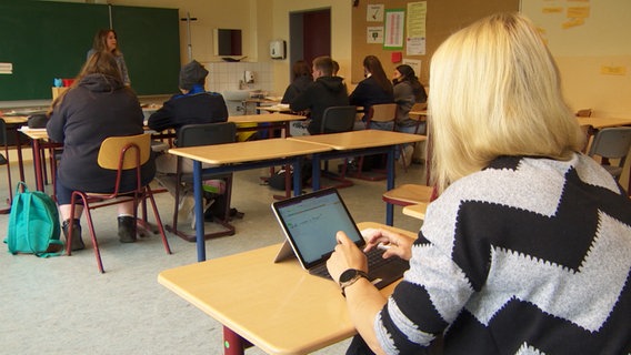 Eine Lehrerin steht vor einer Schulklasse und unterrichtet. Eine Lehrerin steht vor einer Schulklasse und unterrichtet.