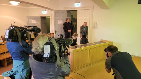 Im Gerichtssaal nimmt der Angeklagte platz, dabei sind viele Kameras aus ihn gerichtet. © Frank Goldenstein Foto: Frank Goldenstein