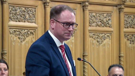 Lübecks Bürgermeister Jan Lindenau steht im Lübecker Rathaus vor einem Mikrofon. © NDR 