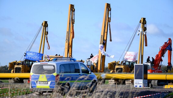 Ein Polizeifahrzeug steht an der Baustelle. Aktivisten haben am Morgen in Brunsbüttel eine Baustelle für Flüssiggas-Pipelines besetzt, um deren Bau zu verhindern und gegen die aktuelle Gas- und Klimapolitik der Regierung zu protestieren. © Jonas Walzberg/dpa Foto: Jonas Walzberg