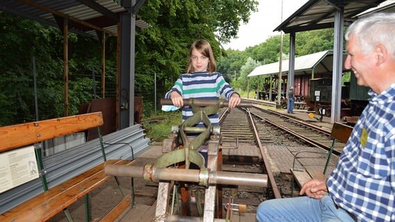 Ein achtjähriges Mädchen und Claus Thiele fahren mit der Draisine über das Gelände des Eisenbahnmuseums Lokschuppen in Aumühle. © Anne Passow Foto: Anne Passow