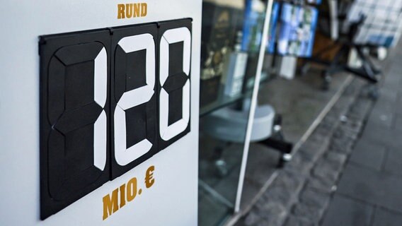 Ein Schild mit der Aufschrift "Rund 120 Mio." steht vor einem Tabak- und Zeitschriften-Geschäft. © Oliver Berg/dpa 