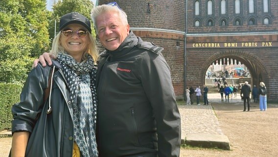 Ein Paar steht vor dem Lübecker Holstentor und lächelt in die Kamera.
. © NDR Foto: Hauke Bülow
