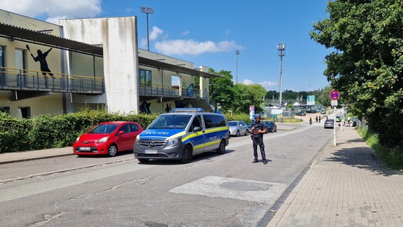 Ein Polizist steht neben einem Einsatzfahrzeug auf der Straße. © NDR Foto: Jannik Wölffel
