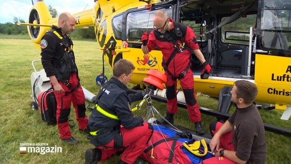Rettungskräfte üben einen Menschen via Hubschrauber transportfähig zu machen.  