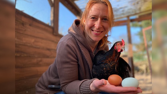 NDR 1 Welle Nord Moderatorin Mandy Schmitt hält ein Huhn und zwei Eier. © NDR Foto: Nina Kohl