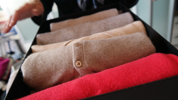 Pullover liegen ordentlich gefaltet in einem Schuhkarton. © NDR Foto: Jennifer Lange