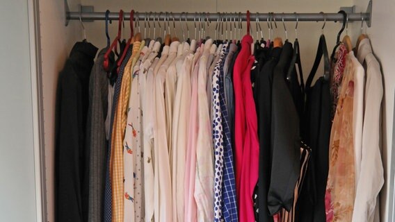 In einem Schrank hängen viele Kleider und Oberteile dicht an dicht. © NDR Foto: Jennifer Lange