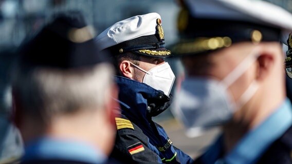 Marinesoldaten schauen auf das Flottendienstboot Alster. Auf dem Bild sind drei von ihnen mit Masken zu sehen. © dpa-Bildfunk Foto: Axel Heimken/dpa