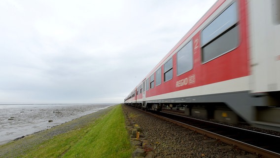 Eine Regionalbahn der Deutschen Bahn fährt über den Hindenburgdamm zwischen Sylt und Niebüll. © picture alliance / dpa Foto: Carsten Rehder