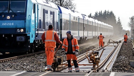 Bahnarbeiter befestigen auf der Marschbahnstrecke, der Strecke zwischen Elmshorn und Westerland auf Sylt, neu verlegte Gleise auf ausgetauschten Schwellen. © dpa-Bildfunk Foto: Markus Scholz