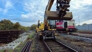 Ein Bagger fährt auf Gleisen bei einer Bahnerneuerung. © NDR 