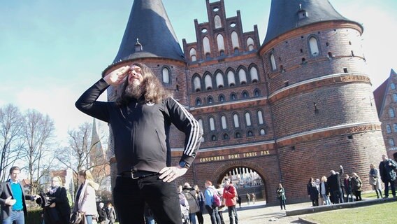 Ein Mann posiert vor dem Holstentor in Lübeck. © NDR Foto: Astrid Wulf