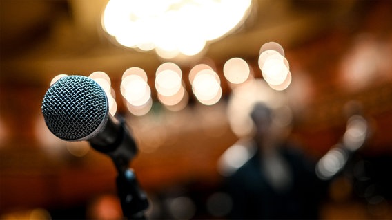 Ein Mikrofon steht auf einer beleuchteten Bühne. © Deutsche Presse-Agentur GmbH/dpa Foto: Britta Pedersen