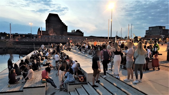Mehrere Menschen versammeln sich in kleinen Gruppen am Abend am Lübecker Drehbrückenplatz. © Johannes Kahts Foto: Johannes Kahts