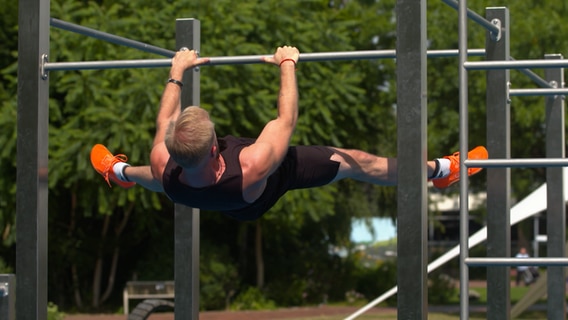 Ein Mann macht einen Klimmzug an einem Sportgerüst. © NDR Foto: NDR