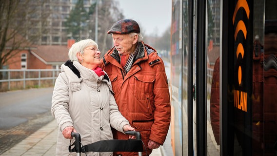 Zwei ältere Menschen lächeln sich beim Einsteigen in einen Bus zu. © Stadtwerke Lübeck 