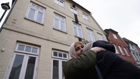 Hava Arslan, Mutter von Yeliz Arslan und Tochter von Bahide Arslan, die beim Brandanschlag auf das Wohnhaus vor 30 Jahren getötet wurden, umarmt vor dem Tatort in der Mühlenstraße 9 ein Mitglied des Freundeskreises zum Gedenken an die Brandanschläge. Hava Arslan, Mutter von Yeliz Arslan und Tochter von Bahide Arslan, die beim Brandanschlag auf das Wohnhaus vor 30 Jahren getötet wurden, umarmt vor dem Tatort in der Mühlenstraße 9 ein Mitglied des Freundeskreises zum Gedenken an die Brandanschläge. © picture alliance / dpa Foto: Marcus Brandt