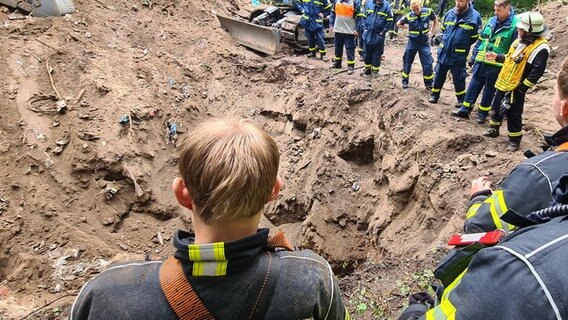 Rettungskräfte stehen an einem Erdloch © NDR Foto: Cassandra Jane Arden