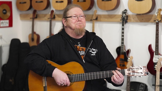 Ein Mann sitzt und spielt Gitarre. Ein Mann sitzt und spielt Gitarre. © NDR Foto: Hauke Bülow