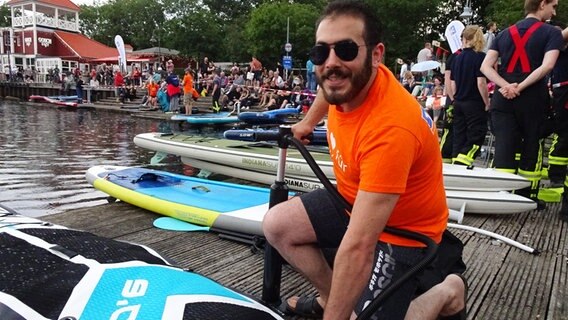 Ein Mann pumpt sein SUP-Board auf im Flensburger Hafen beim NDR Sommer Festival. © NDR Foto: Peer-Axel Kroeske