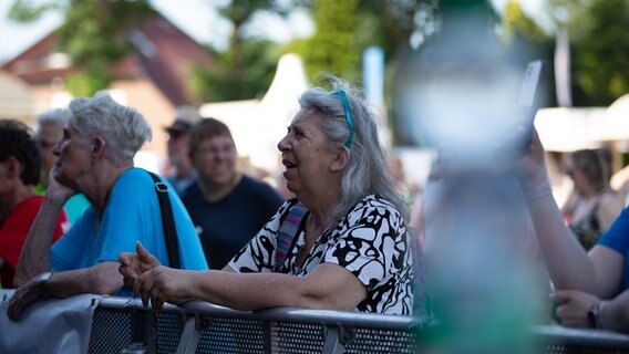 Frau mit weißen Haare und einem schwarz-weißen Oberteil singt in der ersten Reihe von der Bühne mit. © NDR Foto: Dominik Dührsen