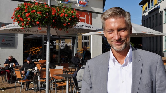 Ralph Godbersen auf dem Gänsemarkt in Neumünster. Dort, wo jetzt die Bäckerei ist, stand einst sein Reisebüro. Ralph Godbersen auf dem Gänsemarkt in Neumünster. Dort, wo jetzt die Bäckerei ist, stand einst sein Reisebüro. © NDR Foto: Anne Passow