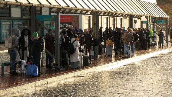 Personen stehen an einem Busbahnhof und warten auf den Bus © Daniel Friederichs Foto: Daniel Friederichs