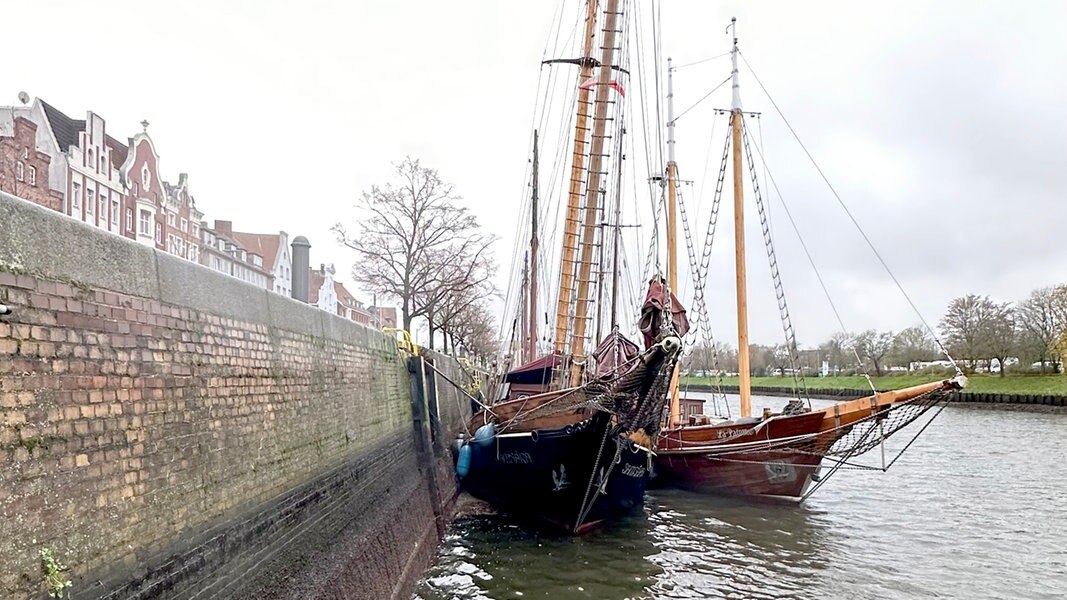 Ein an der Kaimauer in Lübeck festgemachtes Schiff liegt schief im Niedrigwasser.