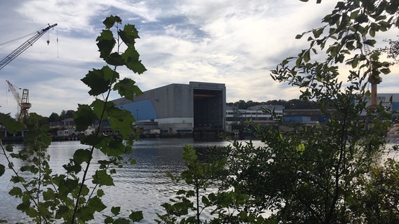 Das Dockgebäude der Werft Nobiskrug in Rendsburg steht vor leicht bewölktem Himmel. © NDR Foto: Arne Helms