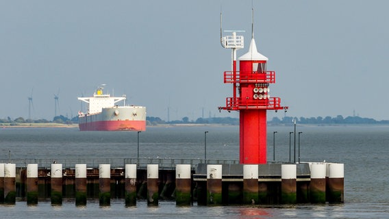Roter Leuchtturm Mole 2 an der Schleuse Brunsbüttel (Kreis Dithmarschen) mit Frachtschiff im Hintergrund. © picture alliance / Zoonar | Conny Pokorny 