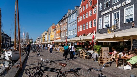 Passanten spazieren am Nyhavn entlang, dem bei Touristen beliebten Hafen mit seinen bunten Häuschen. © picture alliance/dpa Foto: Jochen Tack