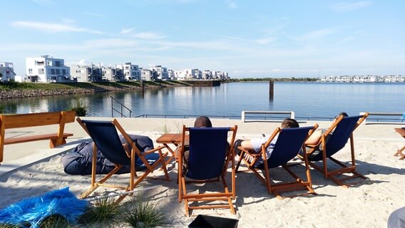 Urlauber in Liegestühlen blicken auf das Ostseeresort Olpenitz. © NDR Foto: Peer-Axel Kroeske