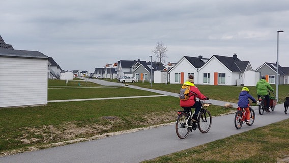 Fahrradfahrer fahren an einer Wohnsiedlung vorbei. © NDR Foto: Peer-Axel Kroeske