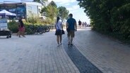 Ein Mann und eine Frau gehen einen Weg entlang zum Timmendorfer Strand.  Foto: Torsten Phillipps