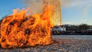 Menschen bewundern das Osterfeuer in Travemünde.  Foto: Phillip Kamke