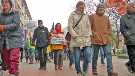 Menschen mit Fahnen und Transparenten demonstrieren in Kiel für den Frieden. © NDR 